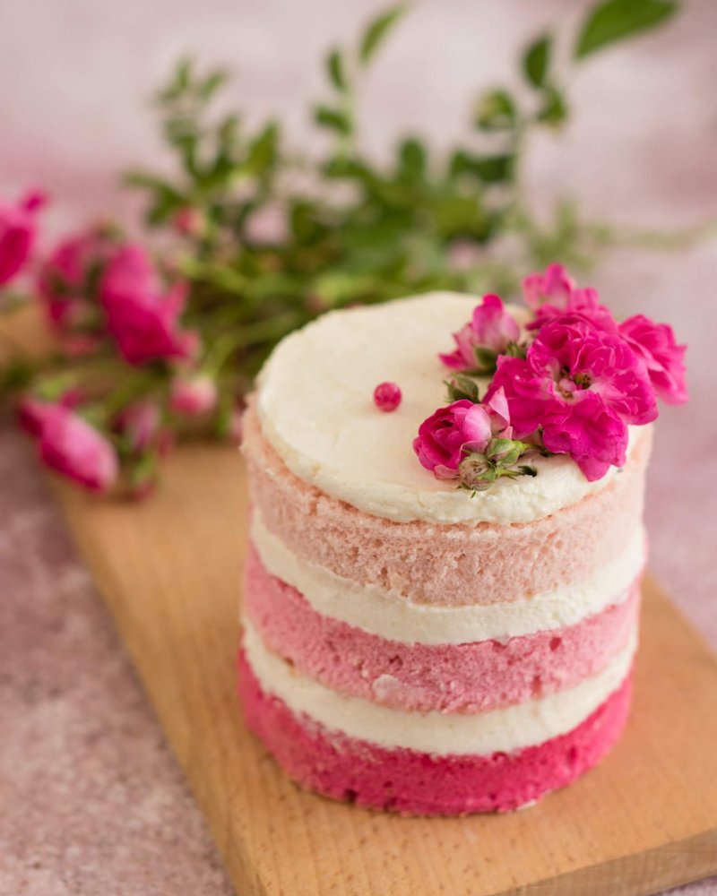 Beautiful pink cream and berries cake on a light concrete background